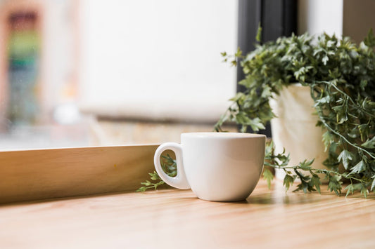 Une tasse de café à côté d'une plante